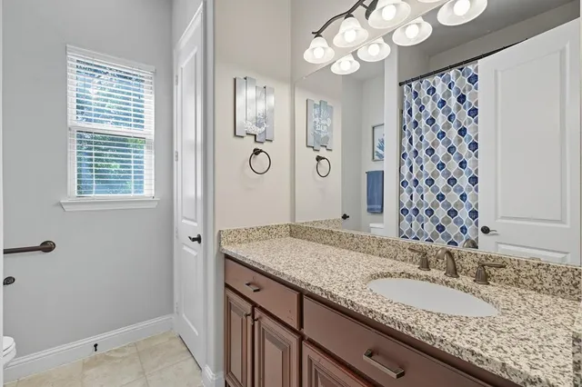 a bathroom with a granite countertop double vanity sink mirror and shower