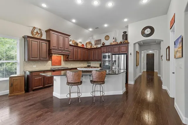 a open kitchen with stainless steel appliances granite countertop a stove and a wooden floors