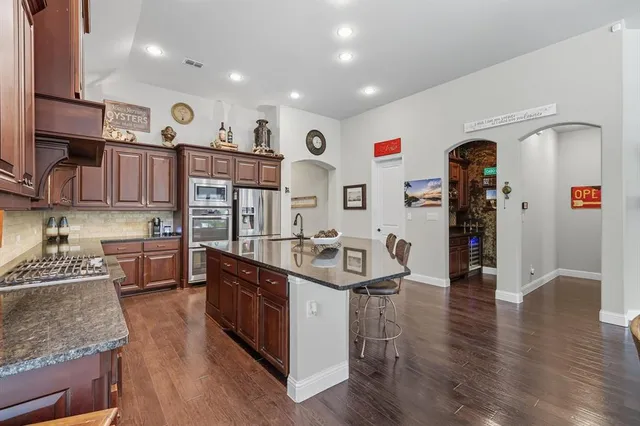 a kitchen with stainless steel appliances granite countertop a lot of counter space and wooden floors
