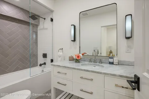 a bathroom with a granite countertop sink mirror toilet and bathtub