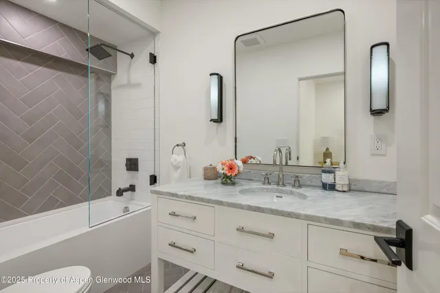 a bathroom with a granite countertop sink mirror toilet and bathtub