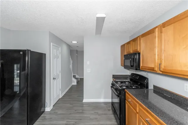 a kitchen with stainless steel appliances granite countertop a refrigerator a stove top oven a sink and dishwasher