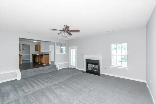 an empty room with fireplace cabinet and windows
