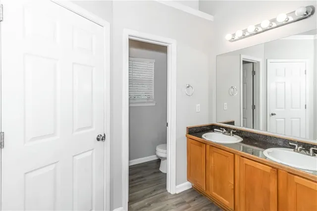 a bathroom with a granite countertop sink a toilet a mirror and shower
