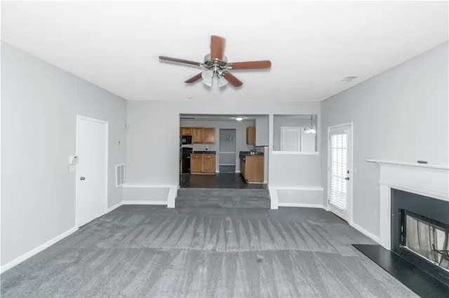 a view of empty room with wooden floor and kitchen view