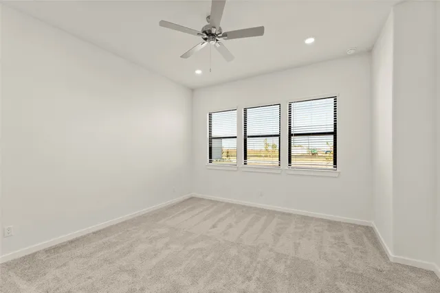 an empty room with windows and ceiling fan view