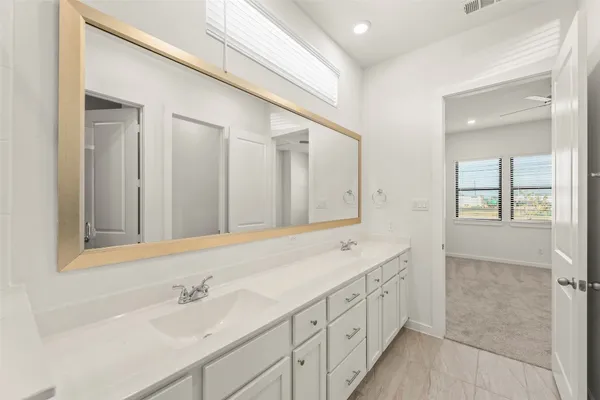 a spacious bathroom with double vanity a mirror and double
