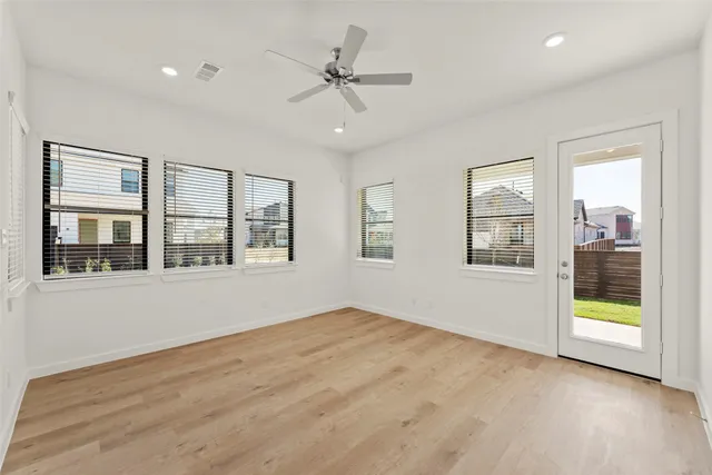 a view of an empty room with a window and wooden floor