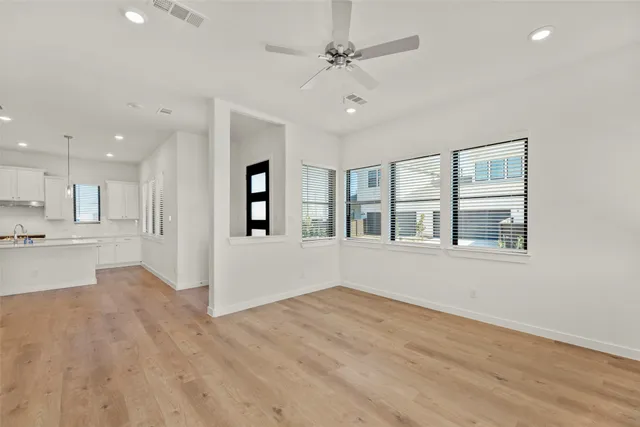 a view of an empty room with a window and wooden floor