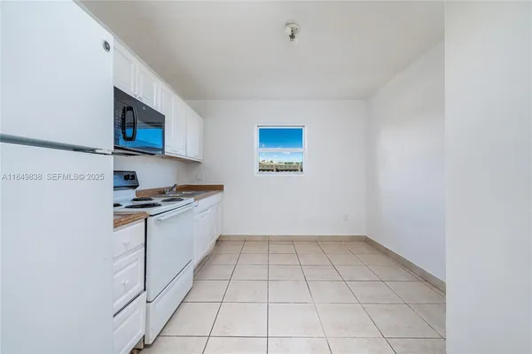 a kitchen with granite countertop a sink a stove top oven and cabinetry