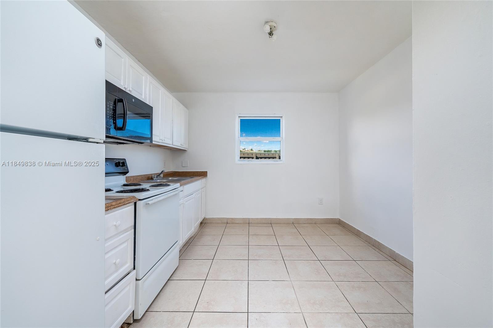 520 Southwest Krome Terrace, Unit 1 Homestead, FL 33030 - Photo 6 of 27 a kitchen with granite countertop a sink a stove top oven and cabinetry