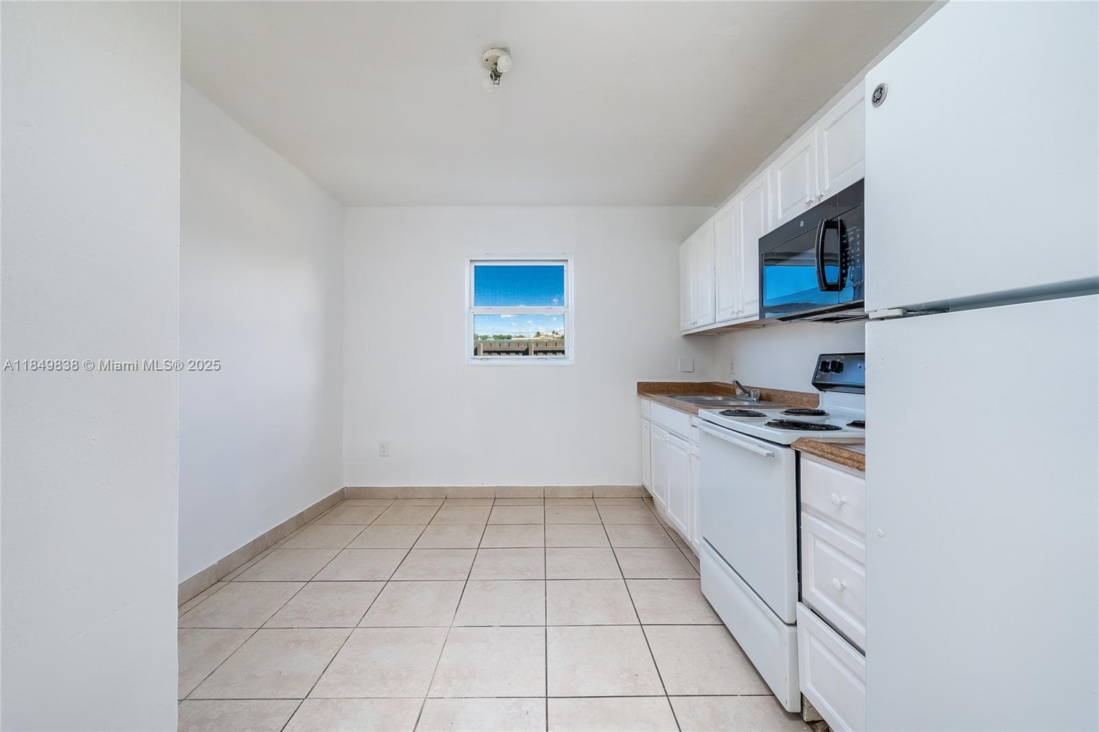 520 Southwest Krome Terrace, Unit 1 Homestead, FL 33030 - Photo 7 of 27 a kitchen with granite countertop a sink a stove top oven and cabinetry