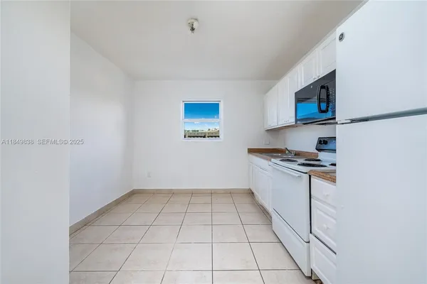 a kitchen with granite countertop a sink a stove top oven and cabinetry
