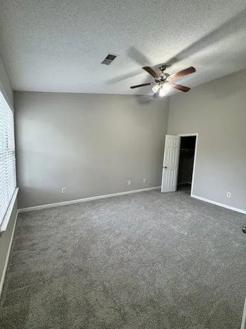 an empty room with windows and fan