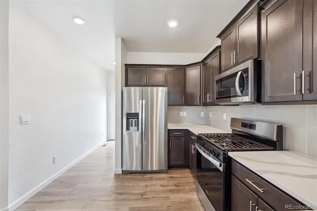 a kitchen with stainless steel appliances granite countertop a refrigerator a stove and a microwave