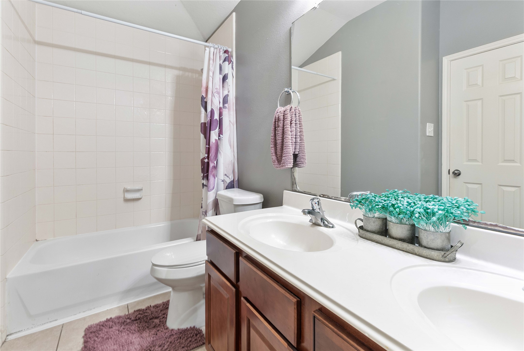 24506 Fort Path Drive Spring, TX 77373 - Photo 31 of 46 Bright and inviting bathroom featuring a double vanity, classic tile shower, and modern fixtures, complemented by warm cabinetry and a decorative touch.