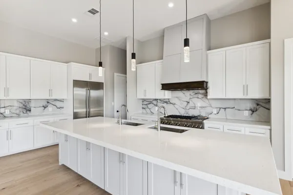 a kitchen with stainless steel appliances a sink a stove a refrigerator and white cabinets