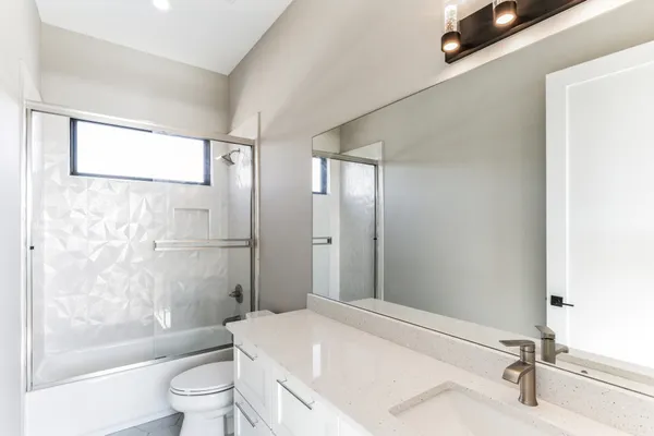 a bathroom with a bathtub shower sink vanity and toilet