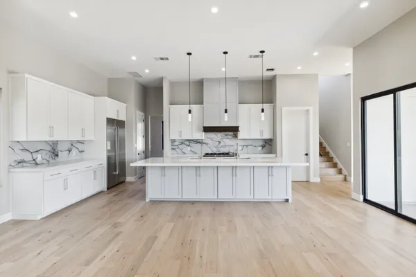 a large kitchen with kitchen island white cabinets and stainless steel appliances