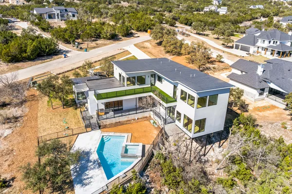 an aerial view of a house with swimming pool and large trees
