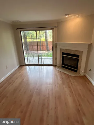 an empty room with wooden floor fireplace and windows