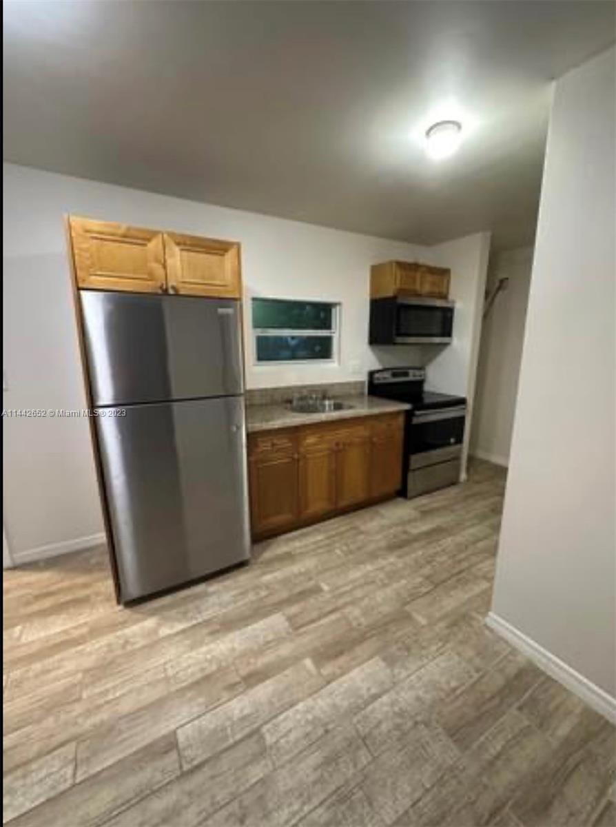2940 Northwest 88th Street, Unit A Miami, FL 33147 - Photo 3 of 5 a kitchen with a refrigerator and a stove top oven