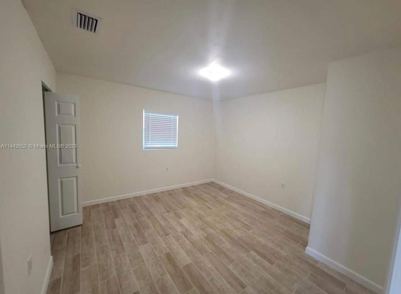 2940 Northwest 88th Street, Unit A Miami, FL 33147 - Photo 5 of 5 an empty room with wooden floor and windows