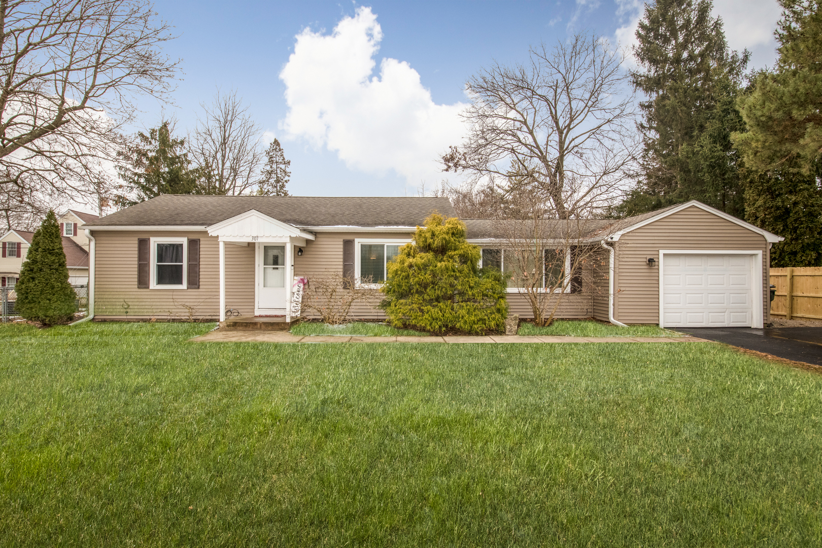 a front view of a house with a garden and trees