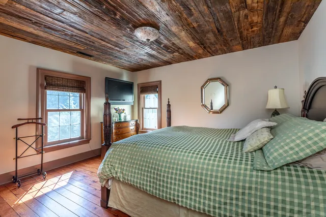 a bedroom with a large bed and wooden floor