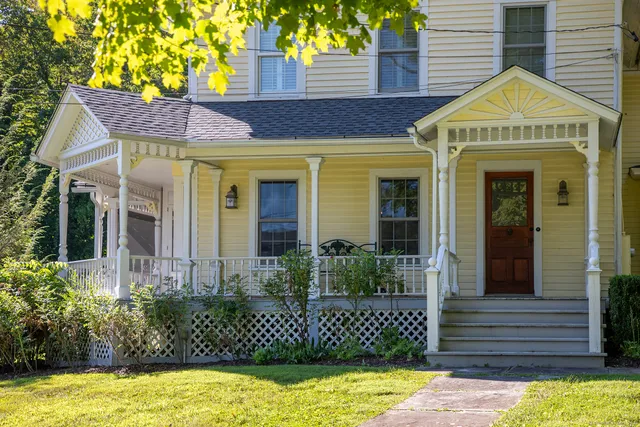 a view of a brick house with plants and large tree