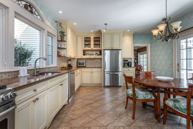 a kitchen with a dining table chairs refrigerator and sink