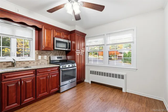 a kitchen with stainless steel appliances granite countertop wooden floors and white cabinets