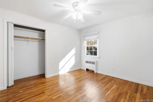 an empty room with wooden floor chandelier fan and windows