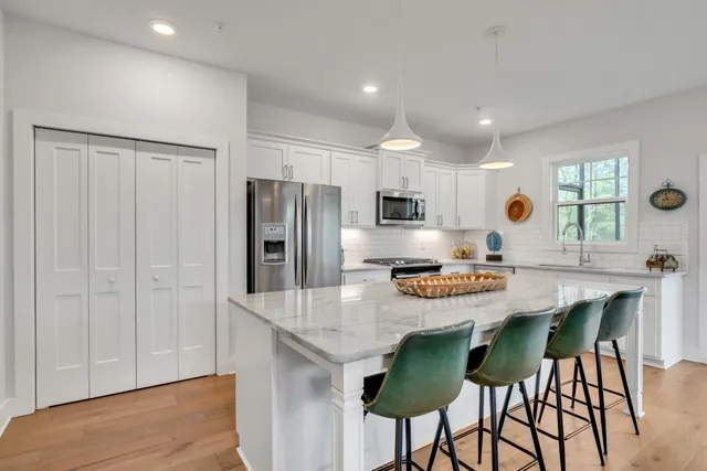 a kitchen with stainless steel appliances kitchen island granite countertop a table chairs microwave and stove top oven