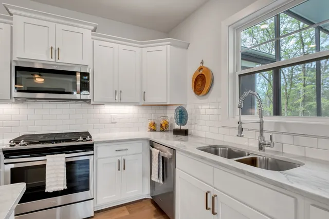 a kitchen with stainless steel appliances white cabinets and a stove top oven