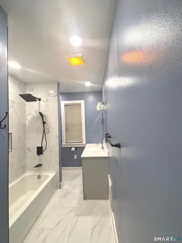 a bathroom with a bathtub a mirror and a shower