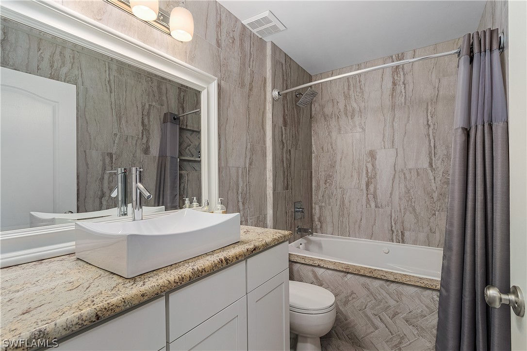 2204 Nelson Road North Cape Coral, FL 33993 - Photo 15 of 22 a bathroom with a granite countertop sink a toilet and bathtub