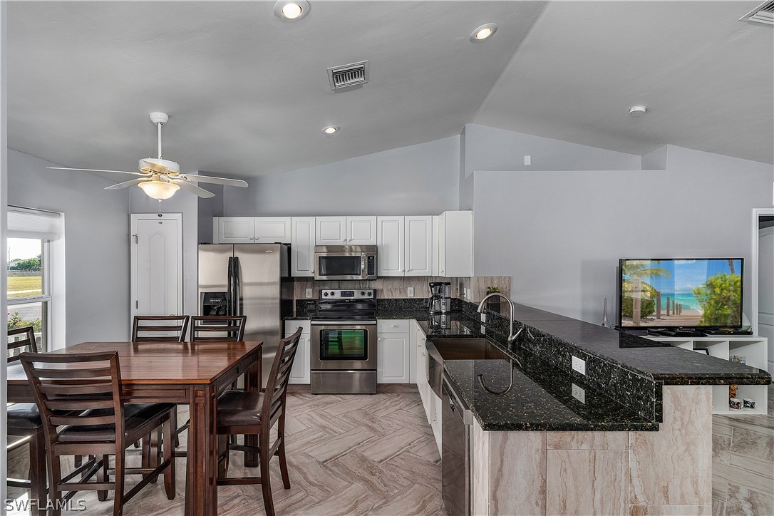 2204 Nelson Road North Cape Coral, FL 33993 - Photo 5 of 22 a kitchen with stainless steel appliances a table and chairs in it