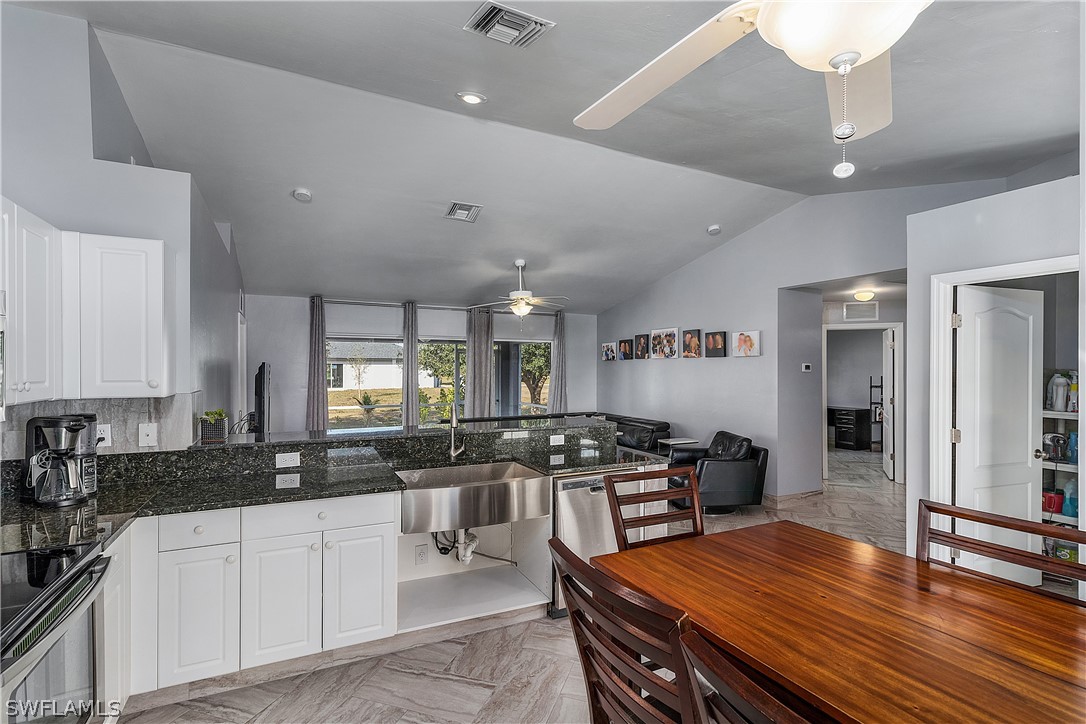 2204 Nelson Road North Cape Coral, FL 33993 - Photo 6 of 22 a kitchen with stainless steel appliances wooden cabinets dining table and chairs