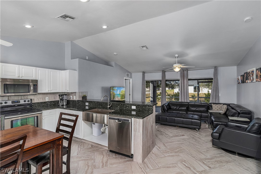 2204 Nelson Road North Cape Coral, FL 33993 - Photo 7 of 22 a kitchen with stainless steel appliances kitchen island granite countertop a stove top oven a sink a dining table and chairs
