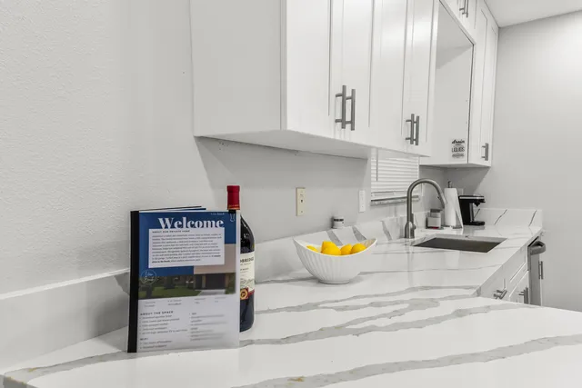 a kitchen with granite countertop white cabinets and white appliances