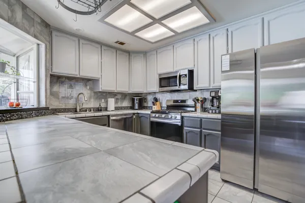 a kitchen with stainless steel appliances granite countertop a sink and a refrigerator
