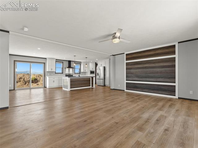 22843 Handle Road Calhan, CO 80808 - Photo 43 of 47 Unfurnished living room featuring light wood-type flooring, a ceiling fan, and wood walls