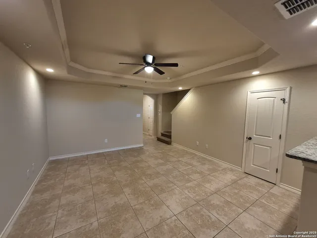 wooden floor in an empty room with a chandelier fan