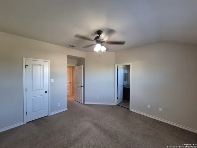an empty room with closet and a ceiling fan