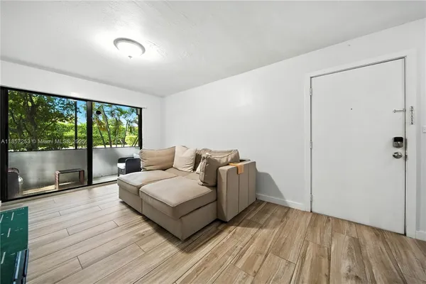 a living room with a bed furniture large window and wooden floor