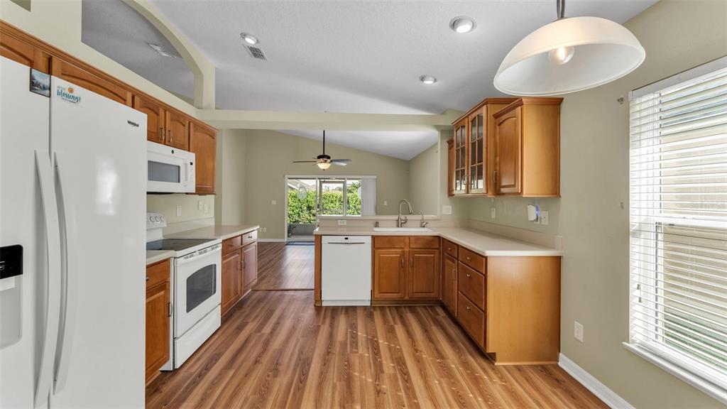 3588 Raleigh Drive Winter Haven, FL 33884 - Photo 14 of 40 a open kitchen with stainless steel appliances granite countertop a refrigerator a sink dishwasher a stove and white countertops with wooden floor