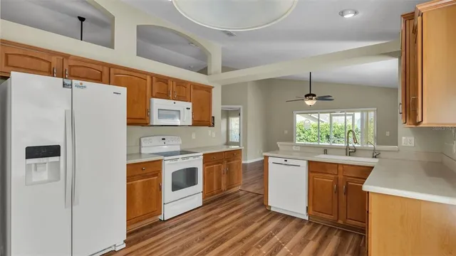 a kitchen with stainless steel appliances a stove a sink dishwasher a refrigerator white cabinets and wooden floor