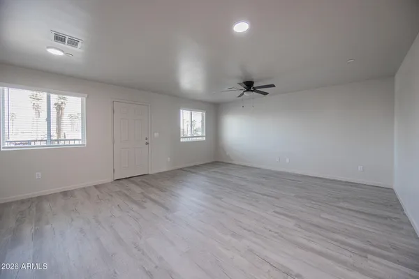 an empty room with wooden floor and windows