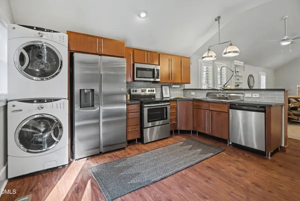 a kitchen with stainless steel appliances granite countertop a sink a stove a washer and dryer